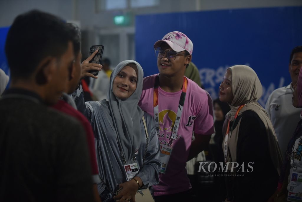 Lifter Banten sekaligus pelatnas yang sukses meraih emas angkat besi kelas 73 kilogram pada Olimpiade Paris 2024, Rizki Juniansyah, menjadi artis dadakan yang dimintai foto bareng oleh sejumlah penonton di sela pertandingan cabor angkat besi kelas 61 kilogram PON Aceh-Sumut 2024 di GOR Angkat Besi, Kompleks Stadion Harapan Bangsa, Banda Aceh, Rabu (4/9/2024).