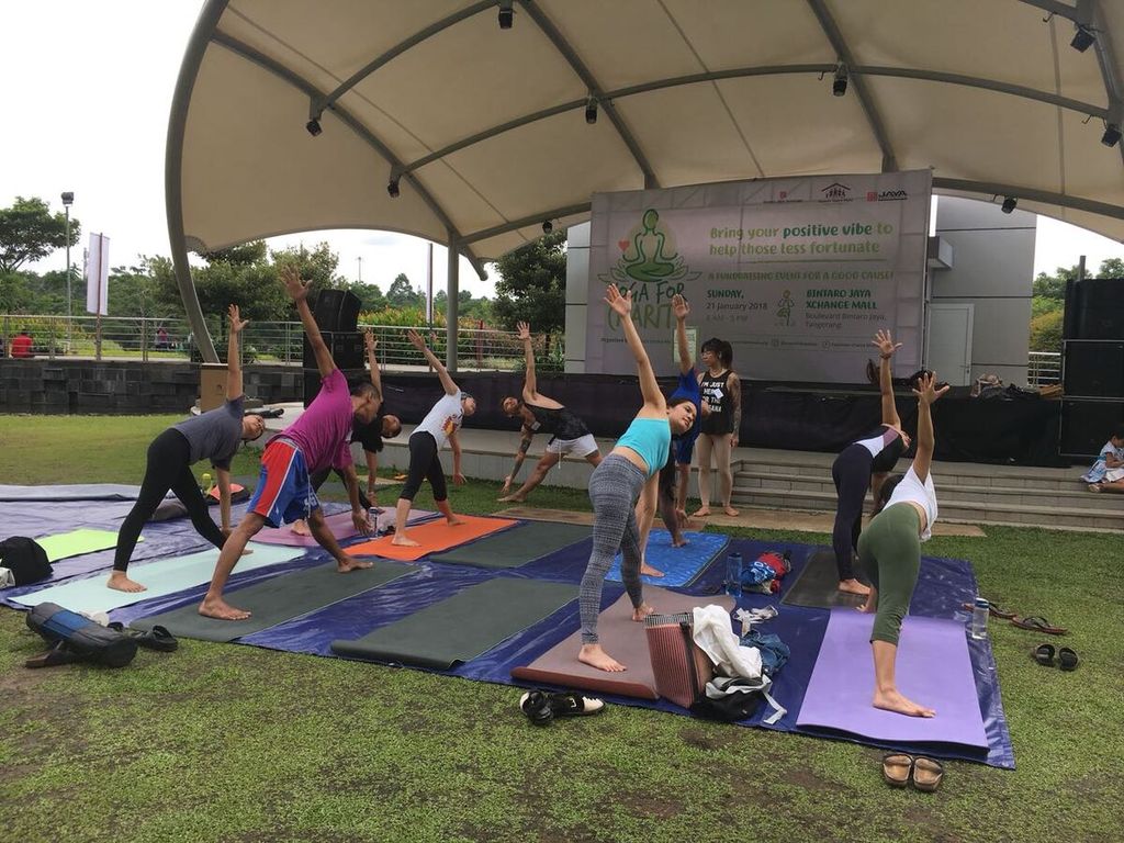 Dua instruktur yoga, April Ulanday (Kanada) dan Adam Smith (Australia), memberikan arahan gerakan dasar yoga yang benar kepada peserta yoga di Taman Interaktif Bintaro Jaya Xchange Mall, Tangerang, Minggu (21/1).