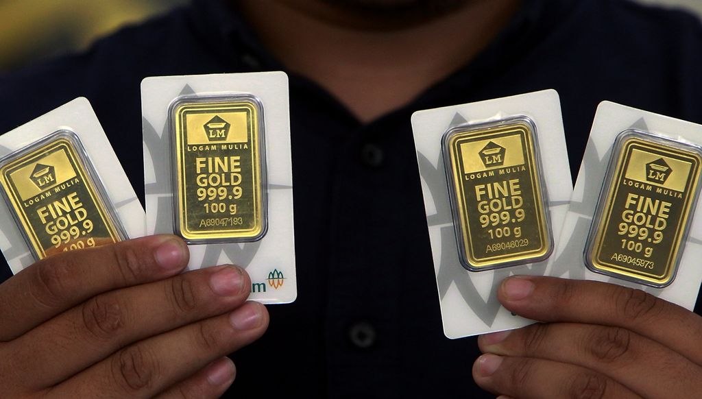 Petugas menunjukkan sejumlah emas batangan 100 gram di Gerai Butik Emas PT Aneka Tambang Tbk, Jakarta. 
