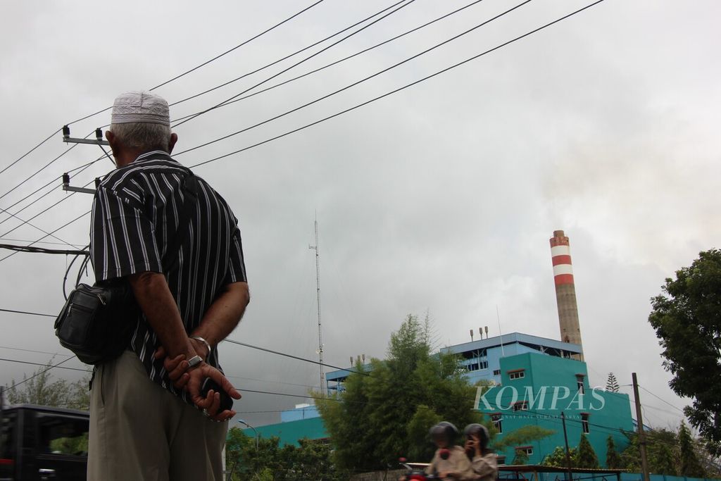 Warga berdiri menghadap Pembangkit Listrik Tenaga Uap (PLTU) 1-2 di Kuala Pesisir, Kabupaten Nagan Raya, Aceh, Sabtu (14/10/2023). PLTU ini menggunaan batubara sebagai bahan bakar pembangkit.