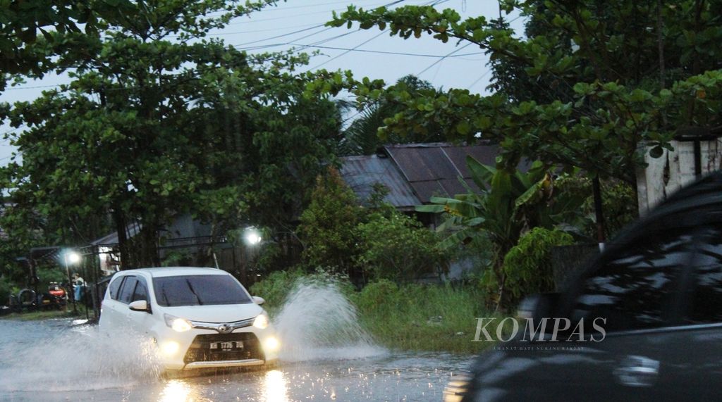 Kendaraan melintas di atas jalan yang digenangi air di Jalan Tingang, Kota Palangkaraya, Kalimantan Tengah, Selasa (13/9/2022). Setidaknya 99 desa dan kelurahan di 28 kecamatan di Kalteng terendam banjir.