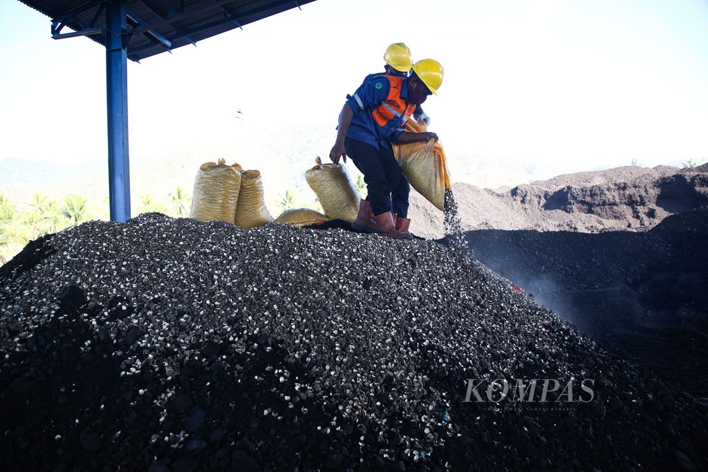 Petugas mencampur cangkang kemiri sebagai sampah biomassa ke batubara yang menjadi sumber energi bagi di pembangkit listrik tenaga uap (PLTU) Ropa di Desa Keliwumbu, Kecamatan Mourole, Kabupaten Ende, Nusa Tenggara Timur, Kamis (7/10/2021).  
