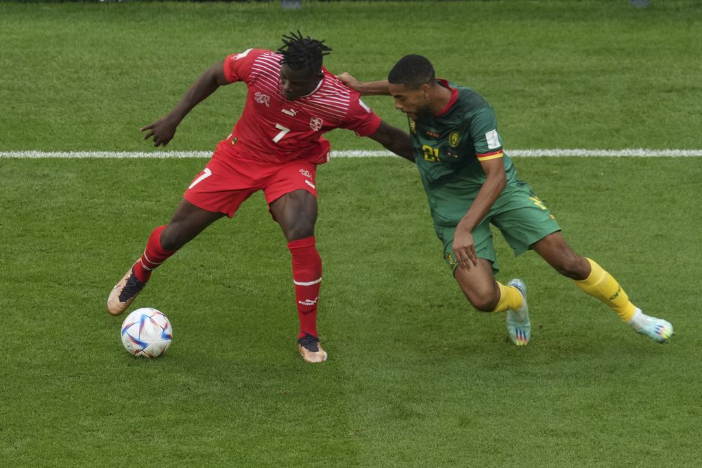 Pemain Swiss Breel Embolo (kiri) berebut bola dengan Jean-Charles Castelletto dari Kamerun saat bertanding di babak fase Grup H Piala Dunia 2022 di Stadion Al Janoub, Qatar, Kamis (24/11/2022). Swiss menang 1-0 