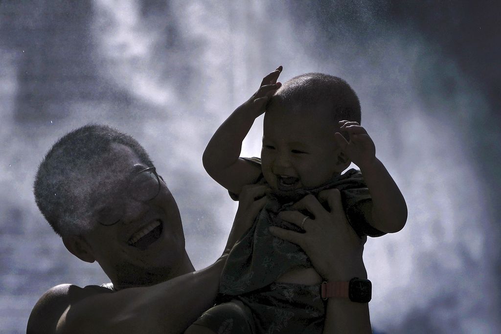 Ayah dan anak bermain di Beijing, China, pada Senin (12/8/2024).