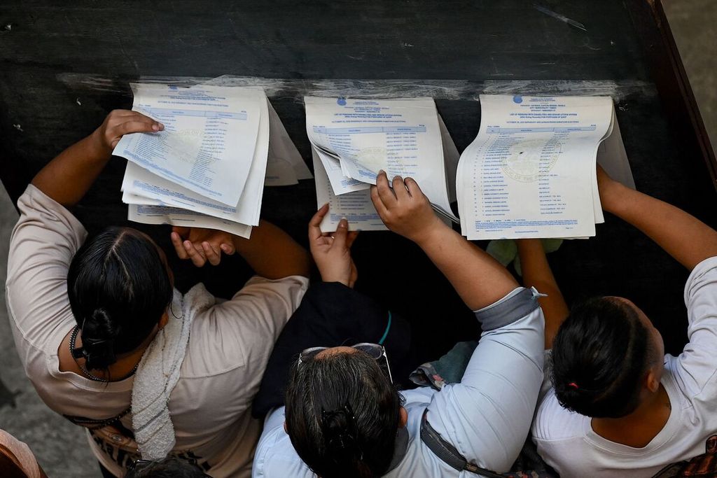 Warga melihat daftar pemilih tetap yang ditempelkan pada papan tulis di depan tempat pemungutan suara di Manila, Filipina, Senin (30/10/2023). 