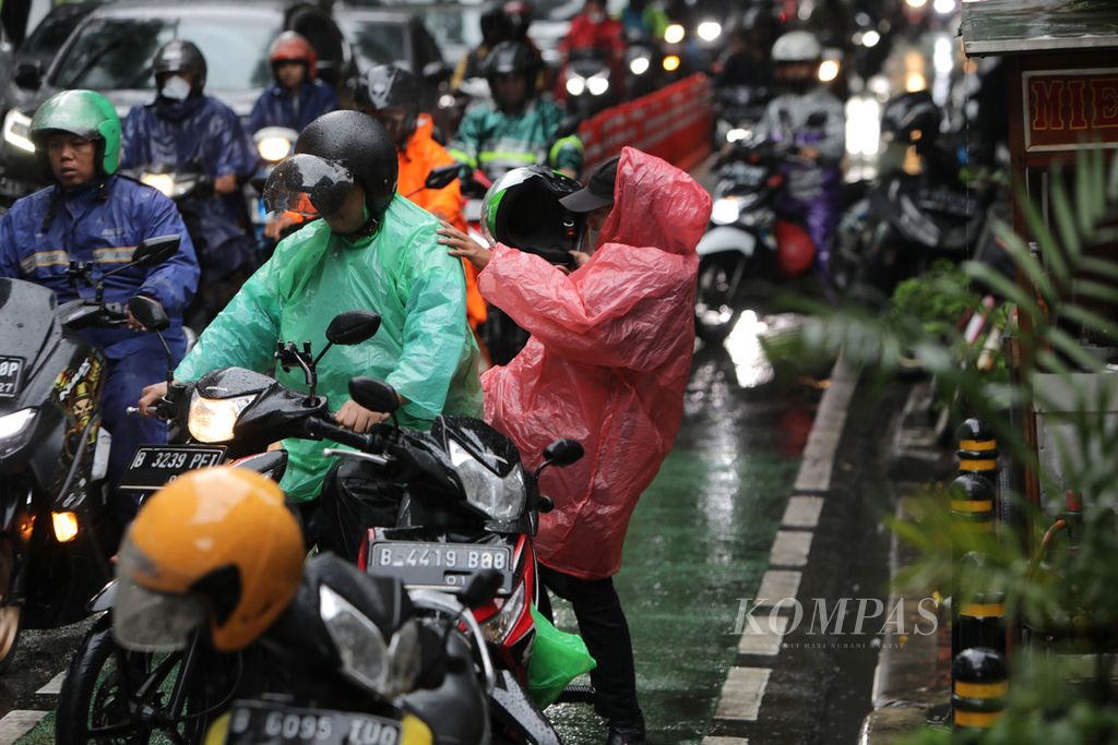 Tukang ojek bersiap mengantar penumpang saat hujan deras di Jalan Tentara Pelajar di sekitar Stasiun Palmerah, Jakarta, Selasa (21/2/2023). Hujan deras membuat sejumlah ruas jalan macet.  