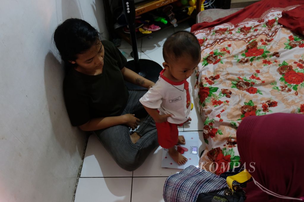 Nurjanah (16, kiri) menemani anaknya yang berusia 15 bulan untuk melakukan pemeriksaan tinggi dan berat badan di rumahnya, Kelurahan Cakung Barat, Kecamatan Cakung, Jakarta Timur, Sabtu (8/4/2023). Pemeriksaan dilakukan oleh kader posyandu secara rutin seminggu sekali setelah anaknya didiagnosis mengalami <i>stunting</i> atau tengkes. Anaknya juga didiagnosis mengalami tuberkulosis (TBC).