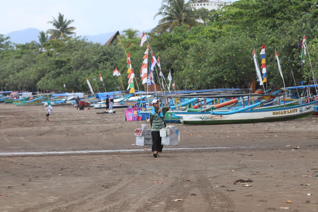 Seorang pedagang asongan berjalan di pinggir Pantai Pangandaran, Kabupaten Pangandaran, Jawa Barat, Selasa (10/11/2020). 