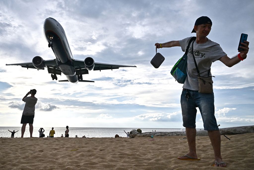Seorang turis berswafoto di Pantai Mai Khao saat pesawat mendarat di Bandara Internasional Phuket di Pulau Phuket, Thailand, 18 November 2023. 