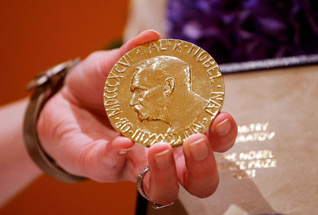 Seorang perempuan memperlihatkan medali Nobel Perdamaian 2021 milik Dmitry Muratov, wartawan Rusia. Kepala Editor Novaya Gazeta itu melelang medali emas 23-karat itu pada lelang di Times Center, New York, Senin (20/6/2022).