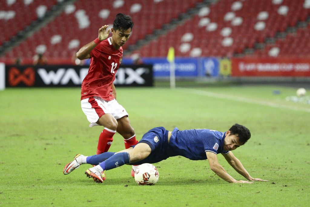 Bek kini tim nasional Indonesia, Pratama Arhan Alif Rifai (kiri), berebut bola dengan pemain Thailand, Supachok Sarachat, pada laga kedua Piala AFF 2020 antara Thailand dan Indonesia di Stadion Nasional Singapura, 1 Januari 2022. 