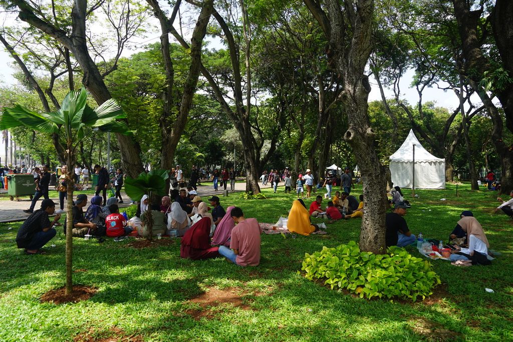 Masyarakat berpiknik di area taman Monumen Nasional, Jakarta Pusatr, pada Minggu (23/4/2024).