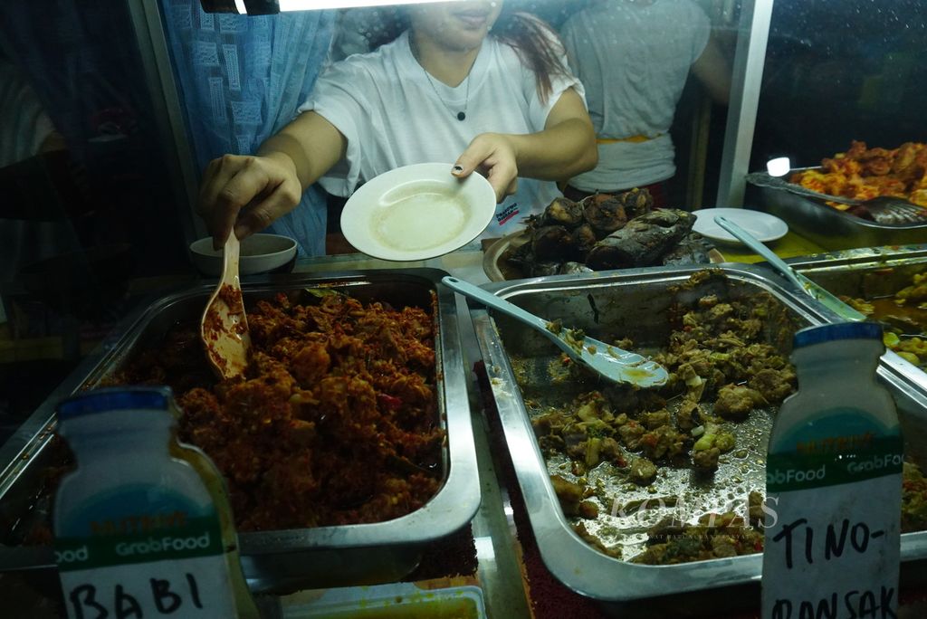 Pelayan mengambil babi rica khas Manado yang dihidangkan di RM Ragey Om Alo di daerah Sario, Manado, Sulawesi Utara, Senin (5/2/2024). Makanan Minahasa terkenal dengan bumbu yang berlimpah dan rasa yang cenderung pedas.