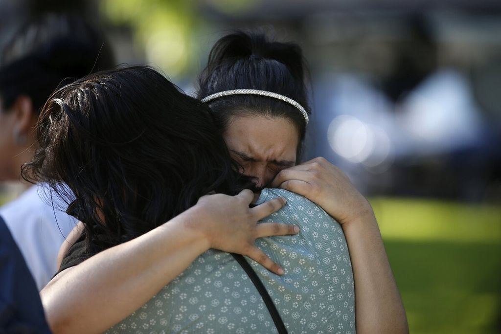 Prianna Ayala, Kamis (26/5/2022), menangis di titik peringatan korban penembakan di sebuah sekolah dasar di Uvalde, Texas, Amerika Serikat. Penembakan yang dilakukan seorang remaja di sekolah itu pada Rabu (25/5) menyebabkan puluhan orang meninggal.  