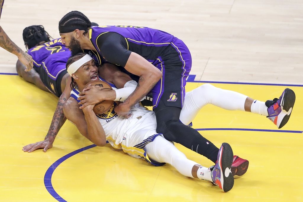 Pemain Golden State Warriors, Moses Moody (bawah), dilanggar oleh pemain LA Lakers, Anthony Davis, dalam pertandingan kedua babak semifinal Wilayah Barat <i>playoff</i> NBA antara Warriors dan LA Lakers di Chase Center, San Francisco, Jumat (5/5/2023) WIB. 
