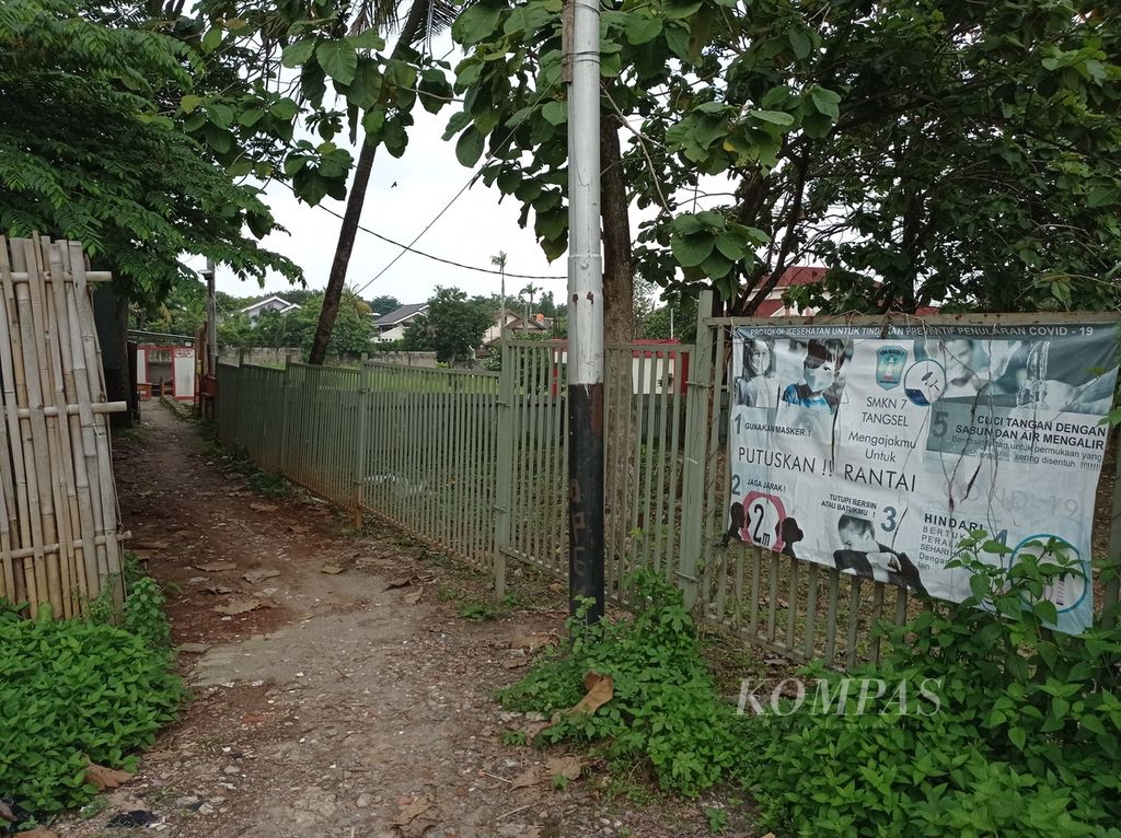 Akses masuk ke SMKN 7 Tangerang Selatan di Kelurahan Rengas, Kecamatan Ciputat Timur, Rabu (27/4/2022). Dari jalan utama terdapat plang sekolah mengarah ke jalan permukiman selebar 2 meter, lalu lahan kosong, dan jalan setapak selebar 1 meter.