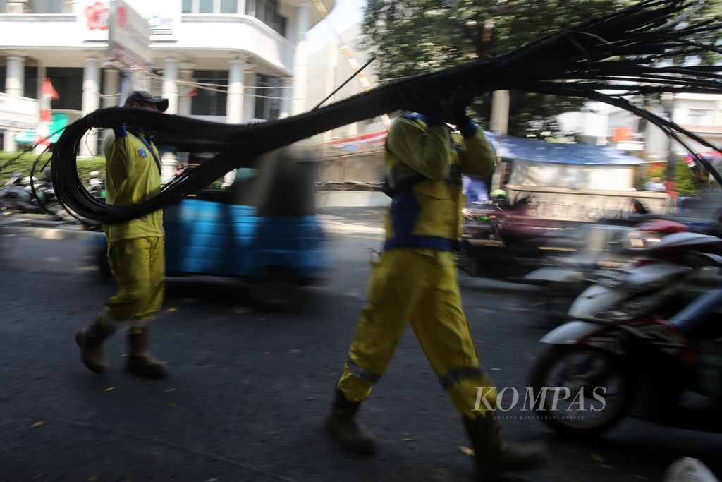 Petugas Suku Dinas Bina Marga Jakarta Pusat mengangkut kabel utilitas udara yang telah dipotong di Jalan Cikini Raya, Jakarta Pusat, Jumat (30/9/2019). 