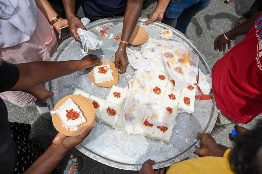 Para pengunjuk rasa membagikan makanan di kompleks Sekretariat Presiden, Jumat (15/7/2022), sebagai perayaan setelah pengumuman mundurnya Presiden Sri Lanka Gotabaya Rajapaksa. (Photo by Arun SANKAR / AFP)