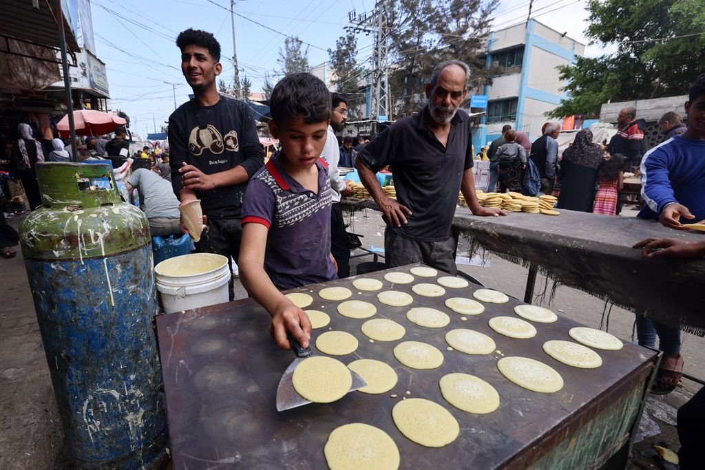 Seorang anak memperlihatkan keahliannya membuat penganan manis yang biasa dihidangkan keluarga Palestina saat perayaan Idul Fitri di Rafah, Jalur Gaza, Minggu (7/4/2024). 