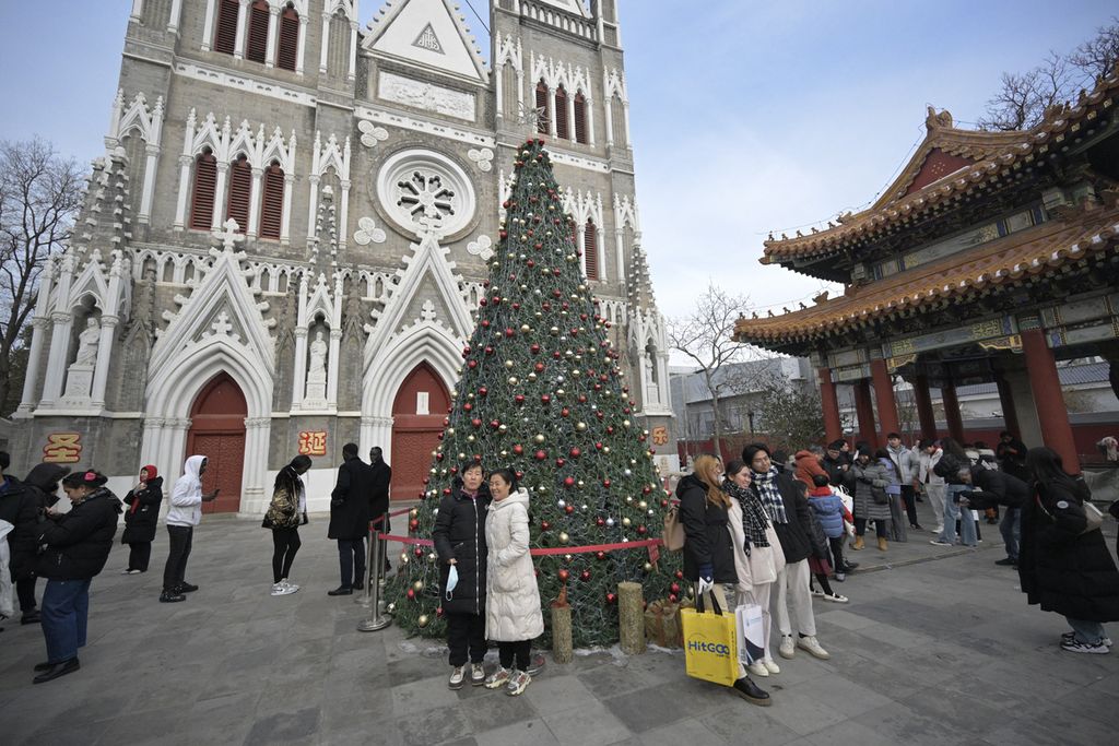 People gather next to the Christmas tree at Xishiku Catholic Church in Beijing, China, Sunday (24/12/2023).