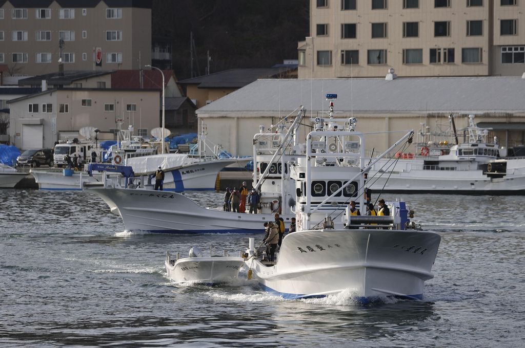 Sebuah kapal nelayan bergegas meninggalkan pelabuhan di Shari, Jepang, Minggu (24/4/2022), untuk ikut mencari dan mengevakuasi korban kapal Kazu I yang dilaporkan hilang kontak sehari sebelumnya.  