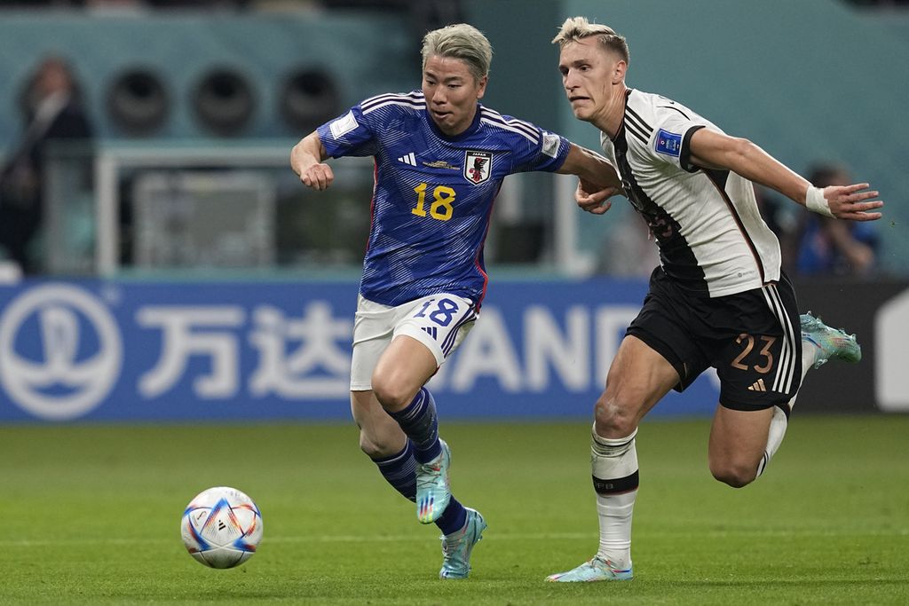 Pemain Jepang Takuma Asano (kiri) menghindari kejaran bek Jerman Nico Schlotterbeck pada laga penyisihan Grup E Piala Dunia 2022 di Stadion Khalifa, Doha, Qatar pada 23 November 2022. Jerman kalah 2-1 pada laga itu.