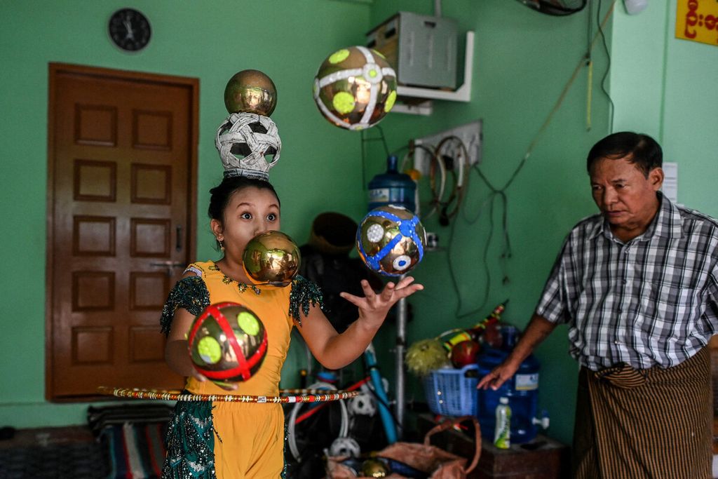 Ohn Myint (kanan) mengawasi cucunya Han Myint Mo berlatih juggling di rumah mereka di Yangon, Myanmar, Selasa (5/7/2022). 