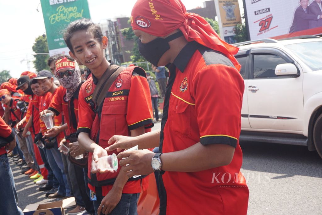 Buruh berbagi minuman dalam unjuk rasa di Bandar Lampung, Lampung, Selasa (1/5/2018). Sekitar 300 buruh yang tergabung dalam Federasi Serikat Buruh Karya Utama (FSBKU) menggelar unjuk rasa dalam rangka Hari Buruh Internasional yang diperingati setiap tanggal 1 Mei.