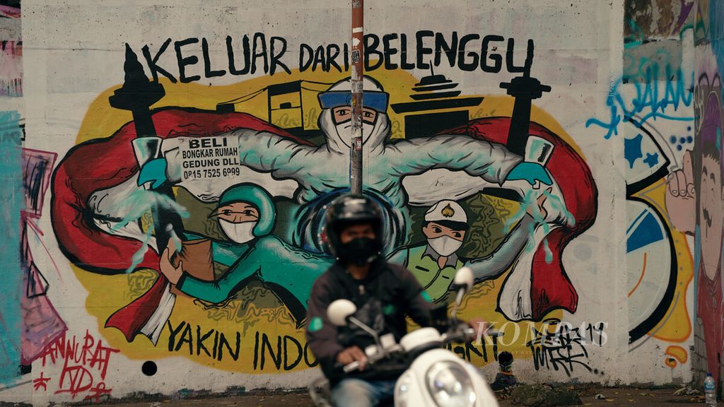Warga melintasi mural berisi ajakan yakin untuk keluar dari belenggu Covid-19 di Bidara Cina, Jatinegara, Jakarta Timur, Selasa (1/2/2022). 
