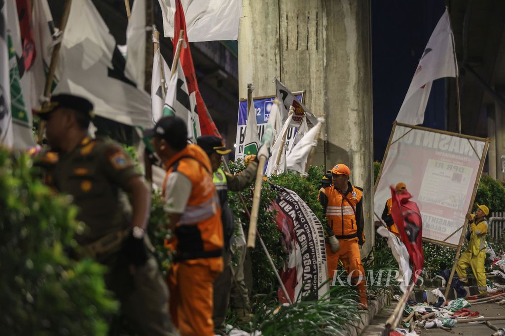 Petugas satpol PP dan PPSU menertibkan bendera peserta Pemilu 2024 di Jalan Kapten Tendean, Jakarta, Minggu, 11 Februari 2024. Badan Pengawas Pemilu DKI Jakarta beserta satpol PP dan pihak terkait menertibkan alat peraga kampanye pada masa tenang Pemilu 2024. Penertiban ini dilakukan serentak di sejumlah wilayah di DKI Jakarta. 