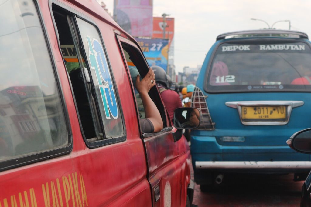 Angkot-angkot sedang menunggu lampu lalu lintas di Jalan Margonda, Depok, Senin (6/2/2023). Sebelumnya, Dinas Perhubungan Kota Depok mencabut 375 izin angkot yang tak laik selama tahun 2022.