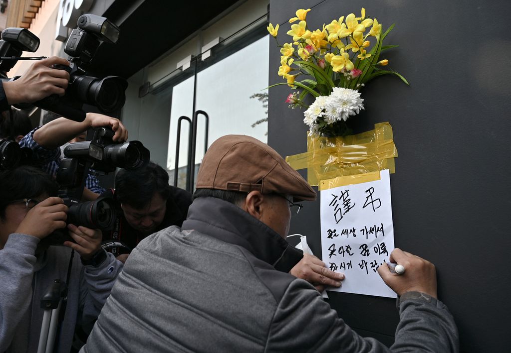 Seorang warga menulis ode pemakaman untuk para korban di lokasi maut tempat pesta Halloween di Distrik Itaewon yang populer di ibu kota di Seoul, Minggu (30/10/2022).