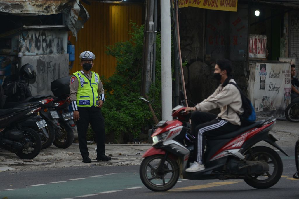 Polisi memperhatikan pengendara di Jalan Mampang Prapatan, Jakarta Selatan, Minggu (20/11/2022). 