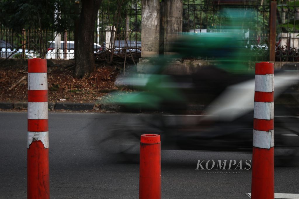 Pengendara sepeda motor melintasi <i>stick cone </i>pembatas jalur sepeda yang rusak di Jalan Tentara Pelajar, Jakarta Pusat, Minggu (12/3/2023). 