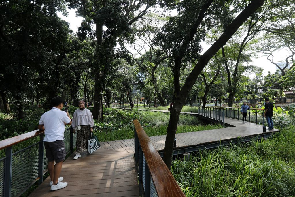 Jalur pedestrian dari kayu yang membelah kawasan taman menjadi salah satu spot berfoto bagi pengunjung Tebet Eco Park, Jakarta Selatan, Senin (23/1/2023). Semakin banyak ruang hijau, aroma kota semakin menyenangkan. 