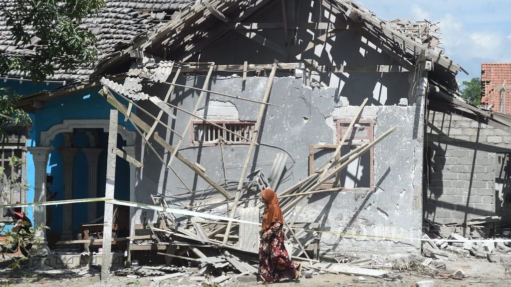 Warga melintasi samping rumah yang rusak oleh ledakan bahan petasan di Desa Karangbendo, Kecamatan Ponggok, Kabupaten Blitar, Jawa Timur, Senin (20/2/2023). Ledakan terjadi pada Minggu (19/2/2023) pukul 22.45. 