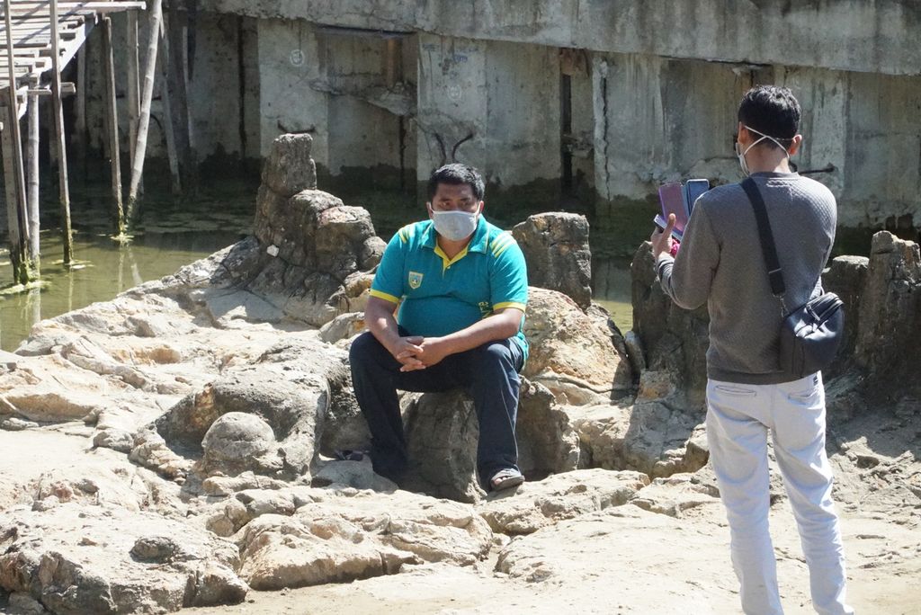 Wisatawan berfoto di samping batu Malin Kundang di kawasan objek wisata Pantai Air Manis, Padang, Sumatera Barat, Sabtu (8/8/2020). Kunjungan wisatawan di Pantai Air Manis mulai kembali ramai pada masa normal baru.