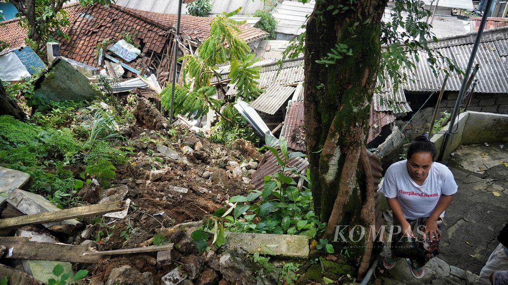 Warga melintasi gang menanjak dengan rumah rusak akibat longsor di Kampung Lebak Kantin, Sempur, Kota Bogor, Jawa Barat, Senin (25/3/2024). 