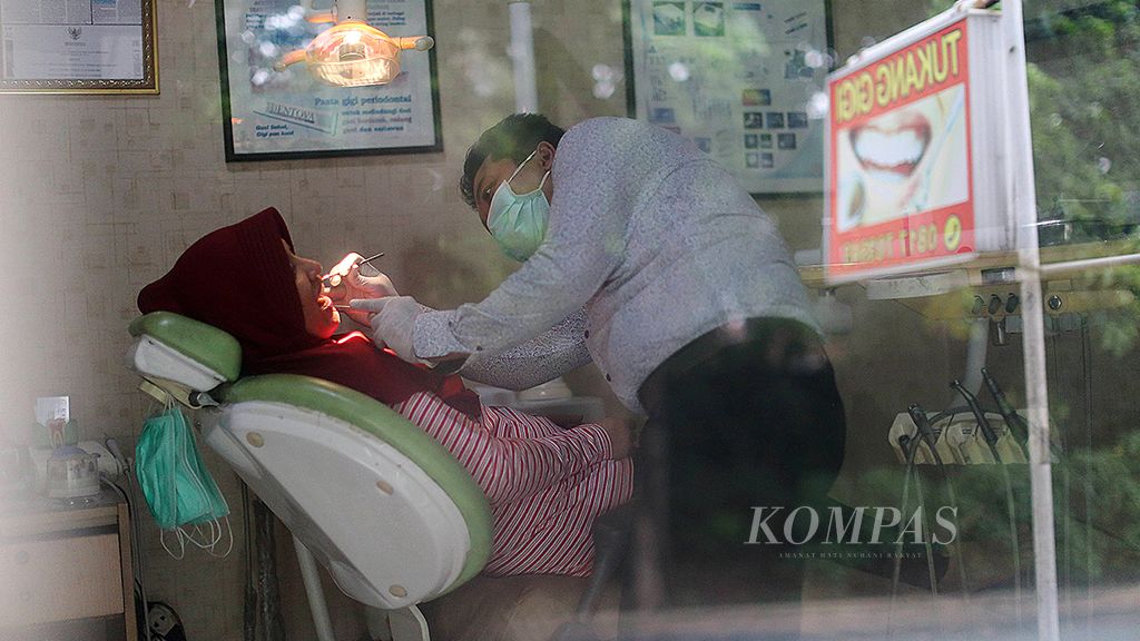Zubaidi, seorang tukang gigi, mengecek kondisi gigi pasiennya di tokonya, di kawasan Ulujami, Jakarta, pekan lalu. Banyak warga yang memasang gigi palsu di tukang gigi karena harganya lebih terjangkau.