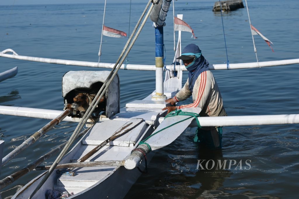 Iwan Ahmad (33), a fisherman on the coast of Pambusuang Village, Balanipa District, Polewali Mandar Regency, West Sulawesi Province, on Friday (22/7/2022) morning tried to push the <i>sandeq </i>boat to land after looking for fish in the sea.