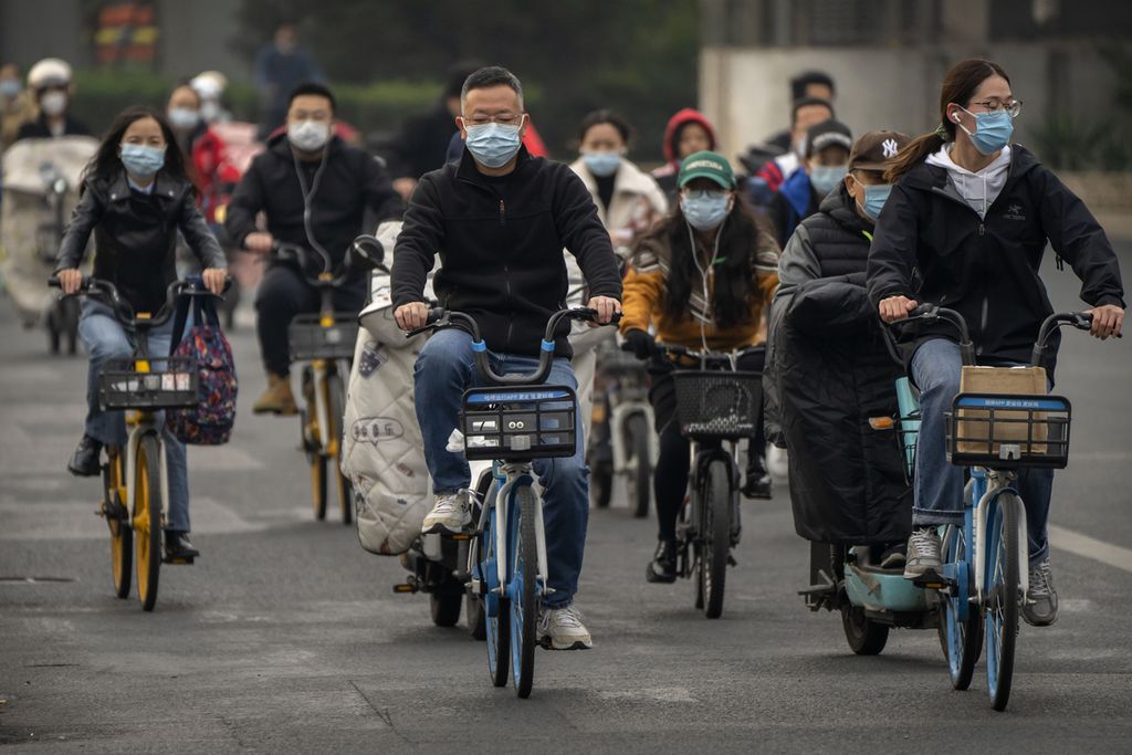 Komuter dengan mengendarai sepeda melintasi sebuah jalan di pusat bisnis di Beijing pada Kamis (20/10/2022)