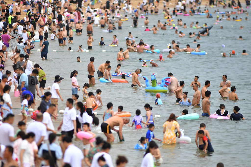Warga mendinginkan diri di Pantai Qingdao, Provinsi Shandong, China, 10 Juli 2022, di tengah gelombang panas yang melanda sebagian wilayah negara itu. 