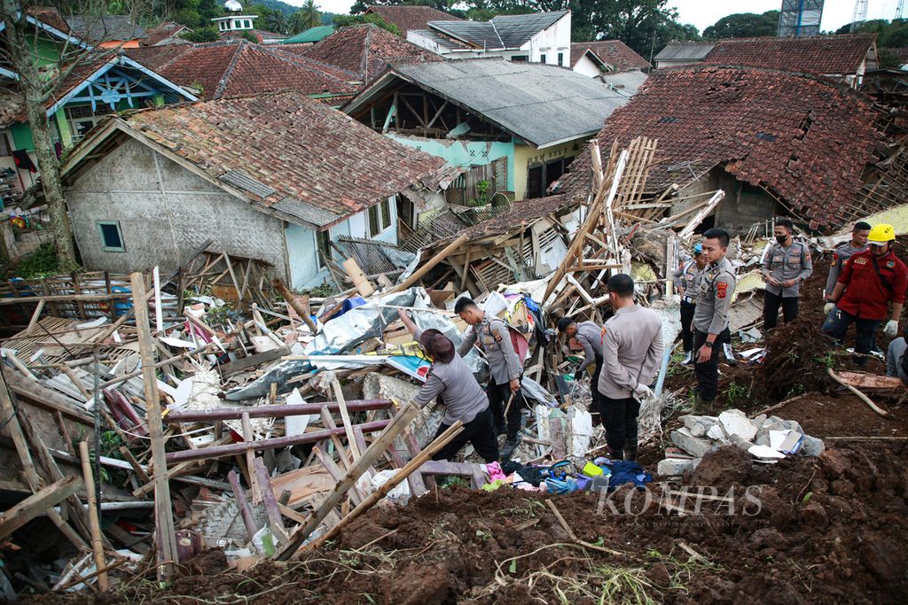 Personel polisi membantu warga mengevakuasi barang-barang dari rumah yang porak-poranda akibat gempa bumi di Desa Cijedil, Kecamatan Cugenang, Kabupaten Cianjur, Jawa Barat, Selasa (22/11/2022).