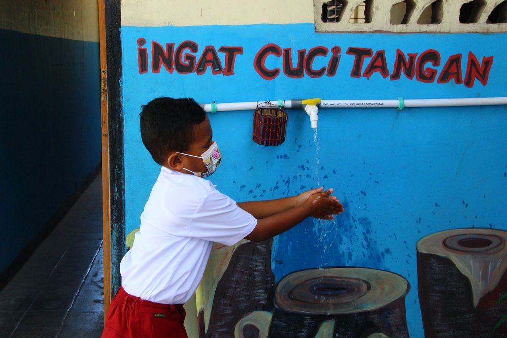 Siswa Sekolah Dasar Katolik Santo Yoseph 1 mencuci tangan sebelum masuk ke dalam areal sekolah. Pembelajaran tatap muka untuk sekolah dasar dan sekolah menengah pertama di Kota Kupang, Nusa Tenggara Timur, dimulai pada Senin (20/9/2021).