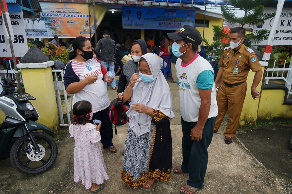 Mudali (57) (bertopi hitam) mengajak anak dan istrinya pulang selepas menjalani vaksinasi di Kelurahan Korumba, Kendari, Sulawesi Tenggara, Senin (21/6/2021). Ratusan warga antusias mengikuti vaksinasi yang diselenggarakan Pemkot Kendari bersama kepolisian ini.