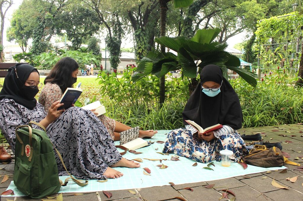 Pengunjung membaca buku di Taman Suropati, Menteng, DKI Jakarta, Minggu (17/7/2022). Di lokasi itu terdapat lemari buku Bookhive yang dapat mendekatkan akses bacaan di ruang publik.