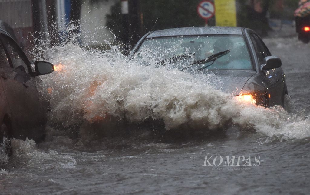 Pengendara mobil menerobos banjir saat hujan lebat di Kecamatan Waru, Kabupaten Sidoarjo, Jawa Timur, Minggu (30/1/2022). Hujan yang berlangsung hampir dua jam tersebut menyebabkan banjir di sejumlah titik di Kecamatan Waru. 