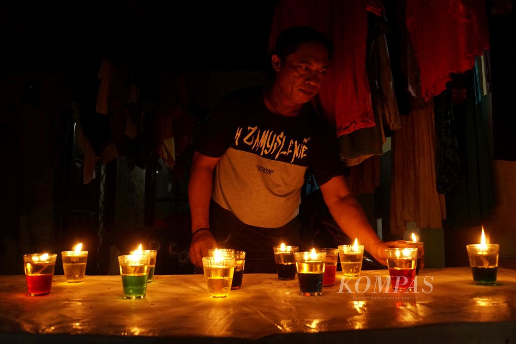 Zainuddin Husain (42) menyalakan lilin yang terpisah ke dalam 14 gelas di depan rumahnya di Ketang Baru, Singkil, Manado, Sulawesi Utara, Senin (3/6/2019). Tradisi yang disebut Tumbilotohe ini dalam bahasa Gorontalo, secara harfiah, berarti menyalakan lampu. Tradisi ini dilakukan pada malam ke-27 Ramadhan yang bertepatan dengan malma pewahyuan atau lailatulkadar.