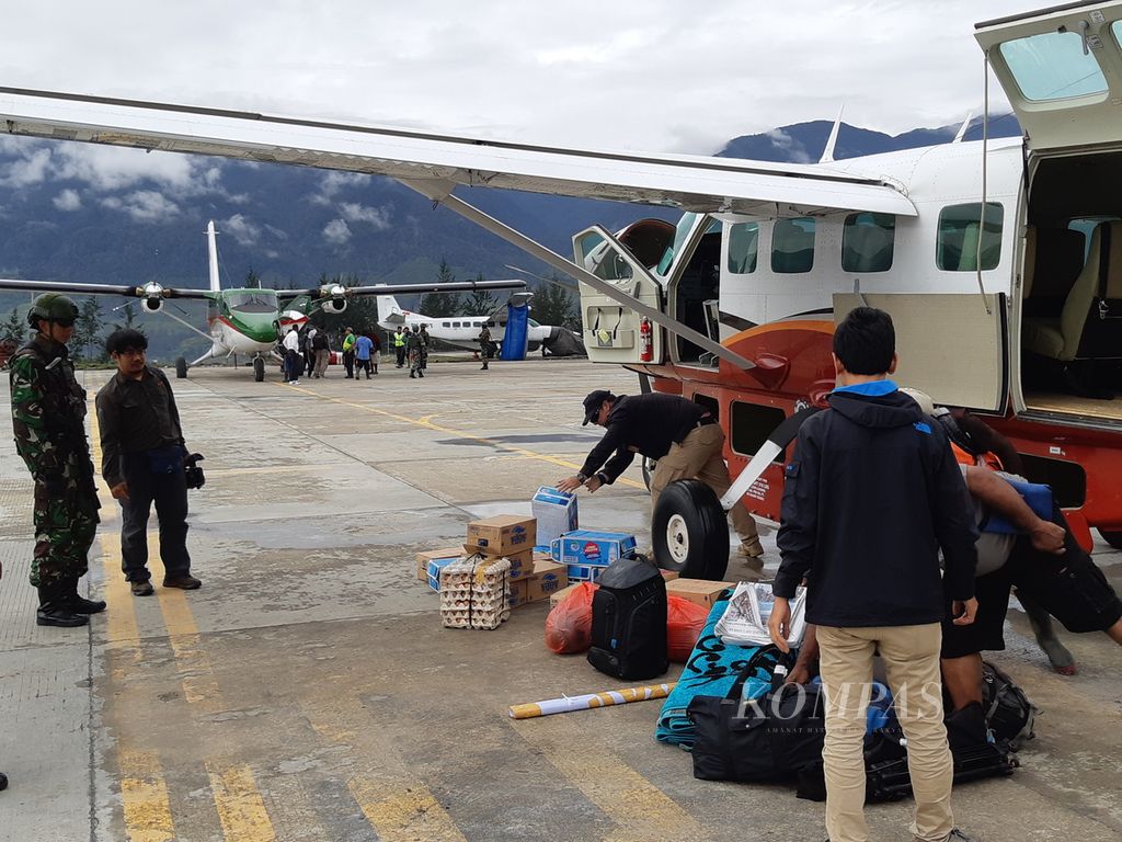 Penumpang menurunkan barang bawaannya dari pesawat di Bandara Ilaga, Kabupaten Puncak, Papua, pada 19 Desember 2019.