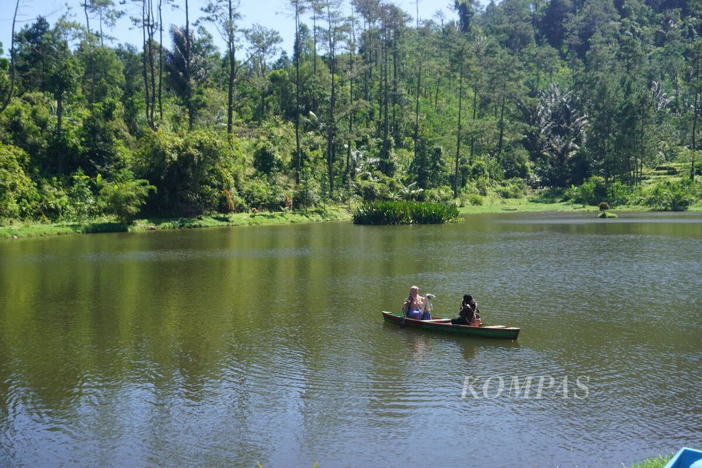 Pengunjung menikmati suasana Telaga Kumpe dengan berperahu di Desa Gununglurah, Kecamatan Cilongok, Kabupaten Banyumas, Jawa Tengah, Rabu (12/7/2023).